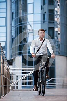 Vertical photo. Businessman in formal clothes with black bicycle is in the city