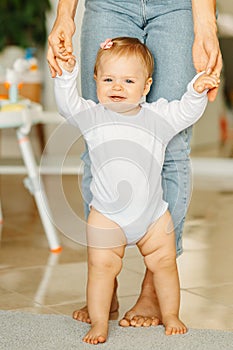 Vertical photo of cheerful baby girl learn to walk indoors