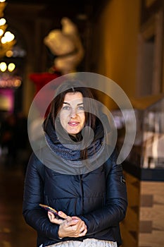 Vertical photo of a cute young european woman against the background of the evening city