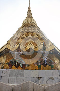 Demon statues holding Golden Chedi prang at Wat Phra Kaew temple. Bangkok, Thailand.