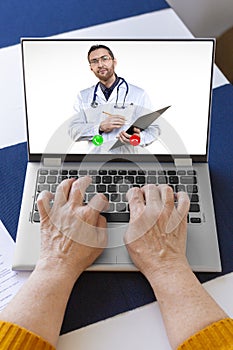 Vertical photo of an elderly woman`s hands on a laptop keyboard during an online consultation with a doctor.