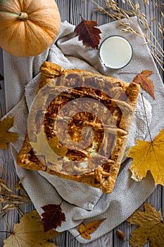 Vertical photo of a festive Thanksgiving pumpkin pie on a light wooden background with textiles, rustic style flat lay