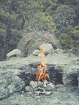 vertical photo, fire from mountain, stones are burning, flame of the Chimera shoots out from under ground. Natural gas