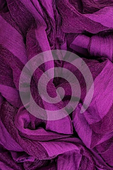 Vertical photo of a fragment of folds of fabric of purple color.