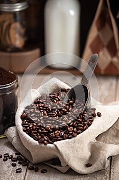 Vertical photo of fresh roasted coffee beans with scoop, espresso grind, milk, cafe