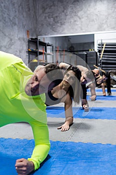 Vertical photo of a group of young people doing gymnastics exercises at the gym