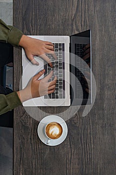 Vertical photo of human hands typing laptop keyboard at coffeeshop