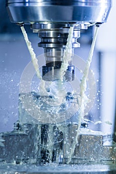 Vertical photo of industrial wet milling process in 5-axis cnc machine with coolant flow under pressure and freezed