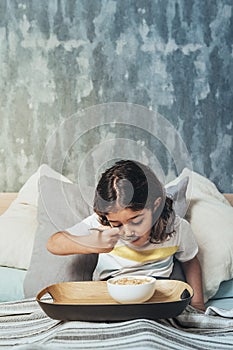 Vertical photo of a kid having a breakfast at bed