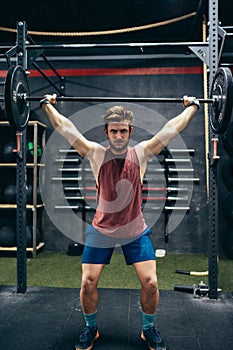 Vertical photo of a man lifting a barbell in a gym
