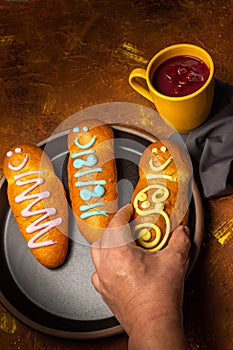 Vertical photo of a man`s hand taking a guagua of bread and a jug of colada morada