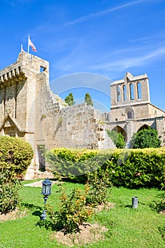 Vertical photo of medieval Bellapais Abbey in Turkish Northern Cyprus. Captured with the adjacent park and with blue sky.
