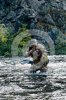 Vertical photo of a mercenary military soldier during a sabotage mission behind enemy lines - he stands knee-deep in the