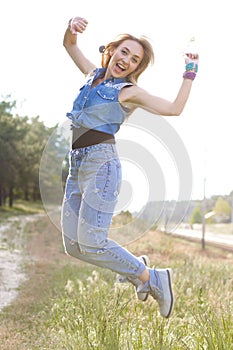 Vertical photo in motion of a cheerful blonde on a background of nature