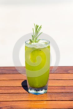 Vertical photo of refreshing cucumber juice cocktail on wooden table at the beach