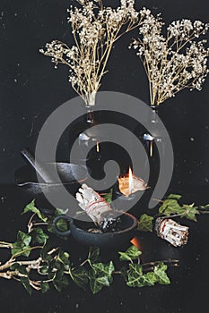 Vertical photo of sage sticks on wiccan witch altar. Two smudge sticks in cast iron holder