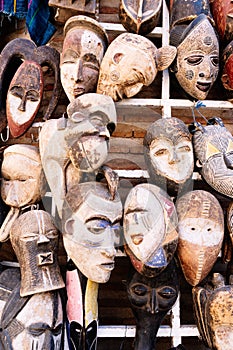 Vertical photo of some wooden masks hanging in a shop in a market