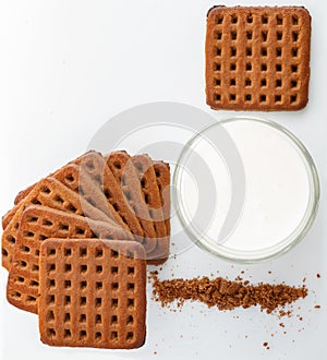vertical photo. square chocolate chip cookies, cookie crumbs with glass of milk on white background