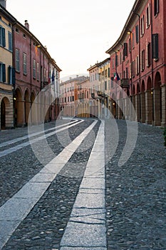 Vertical photo of a street with colorful edifices with white sky background.