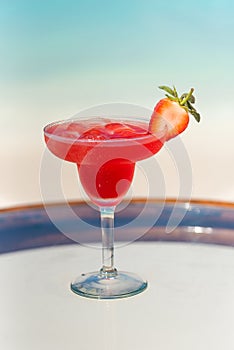 Vertical photo tasty fresh icy strawberry cocktail on the glass table at the beach with ocean