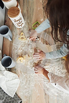 Vertical photo. Top view of kids learning to prepare food from the flour with special formed instruments