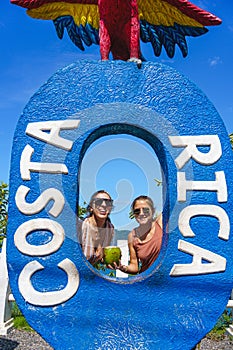 Vertical photo of two caucasian women posing in a figure of a letter in summer