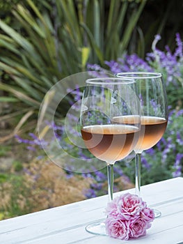 Vertical photo of two glasses of rosÃ© wine in a backyard