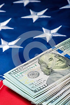 Vertical photo view of a stack of money lying on the flag of the United States of America