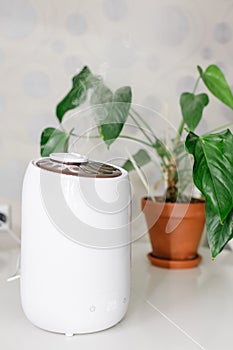 Vertical photo of white air humidifier spreading steam.