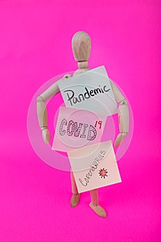 Vertical photo of wooden jointed manikin figure holding signs with Pandemic COVID 19 Coronavirus