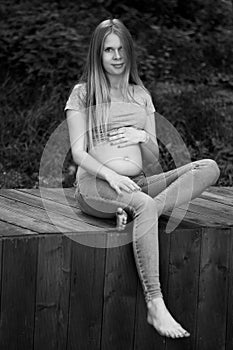 Vertical photo.Young beautiful and happy pregnant girl walks in the park. second trimester. Benefits of walking during pregnancy.