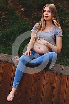 Vertical photo. Young beautiful and happy pregnant girl walks in the park. second trimester. Benefits of walking during pregnancy.