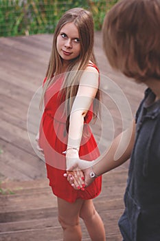 Vertical photo. A young couple a guy and a girl are walking in the park and holding hands. Love story. Pregnancy