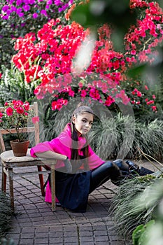 Vertical photo of a young girl on a background of flowering plants in a botanical garden