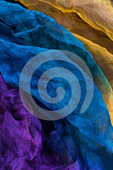 Vertical photograph of fabric dyed in different colors and laid out in waves, to be used as a background
