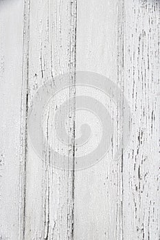 Vertical photograph of old wooden planks painted with white paint that has cracked and fallen off in places due to weather and