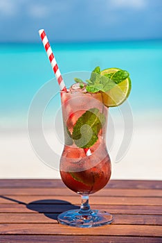 Vertical phto of virgin strawberry mojito cocktail with straw on wooden table at the beach