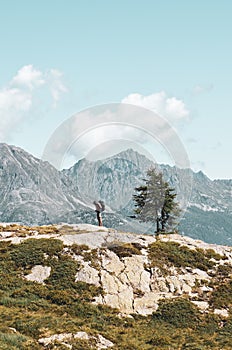 Vertical picture of adventurous man hiking in the mountains. Standing on the edge of a rock. Backpacking traveler. Adventure