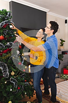 Vertical picture of caucasian couple spending time together decorating the christmas tree