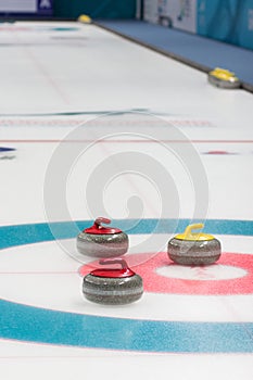A vertical picture of curling stones on top of curling sheet.