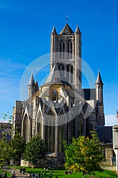 Vertical picture of the facade of Saint Nicholas` Church Sint-Niklaaskerk in a sunny day with green trees of Emile Braunplein a