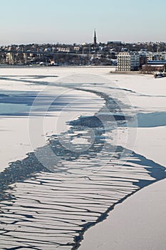 Vertical picture of a frozen river surrounded by buildings in winter in Stockholm in Sweden