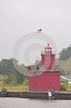 Vertical picture of The Holland Harbor Light surrounded by the water and greenery in the USA