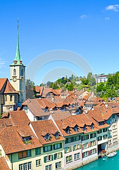 Vertical picture of Nydegg Church and historical buildings located along turquoise Aare River in Bern, Switzerland. Religious