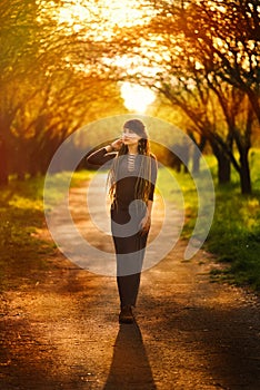 Vertical picture with silhouette of beautiful young woman posing in garden on sunset, boho hippie style, outdoor fashion portrait