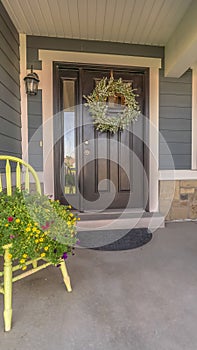 Vertical Porch and facade of home decorated with colorful flowers and wreath on the door