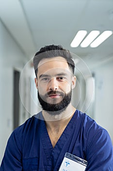 Vertical portrait of bearded caucasian male healthcare worker in hospital corridor, copy space