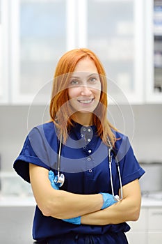 Vertical portrait of beautiful redhead female doctor during appointment of patient in office a modern clinic. Skillful woman