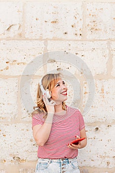 Vertical portrait of a beautiful woman listening to music outdoors with her headphones. top copy space