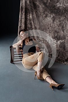 Vertical portrait of a beautiful woman sitting on the floor in the studio